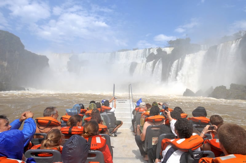 People riding a boat under Iguazu Falls.